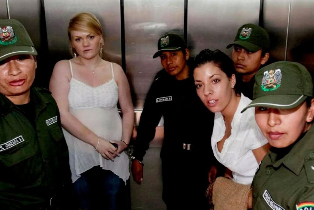 Kaksi naista ja useita viranomaisia hississä Bolivian niin sanotun “Bolivia-saken” oikeuskäsittelyn yhteydessä.