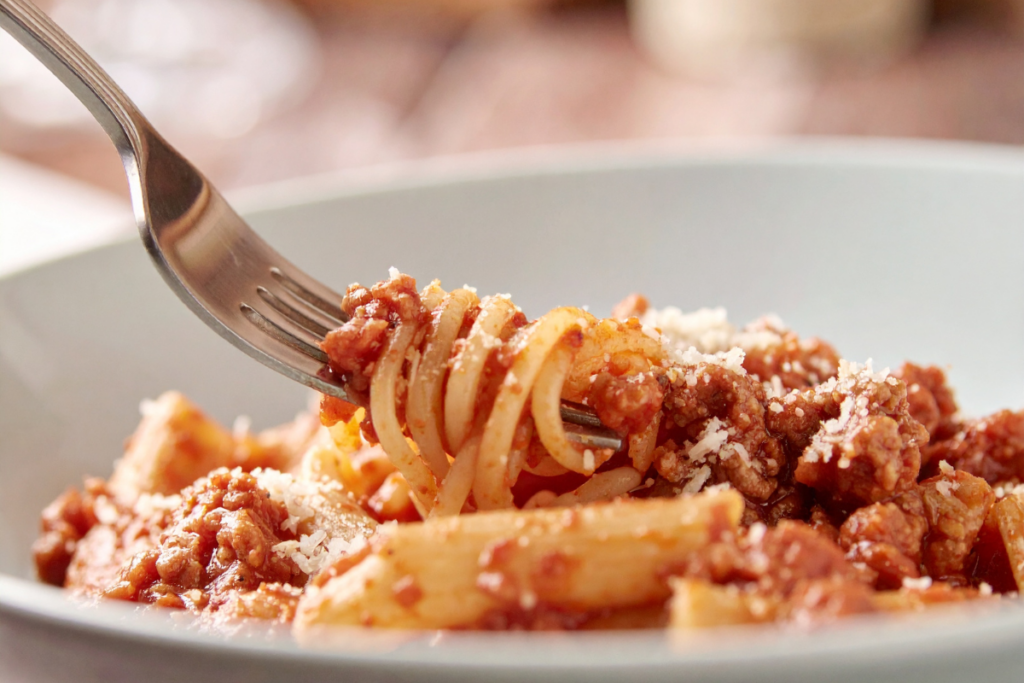 Jauhelihakastiketta ja spagettia kierrettynä haarukkaan.