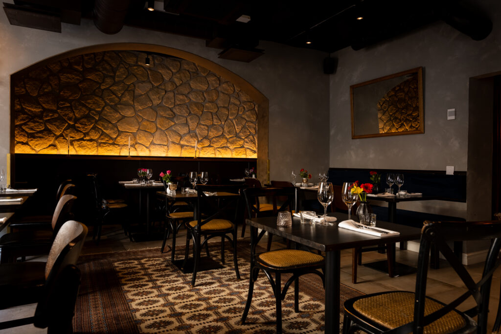 Le Grec ravintolan sisätila, kiviseinä ja intiimi valaistus pöytien yläpuolella.