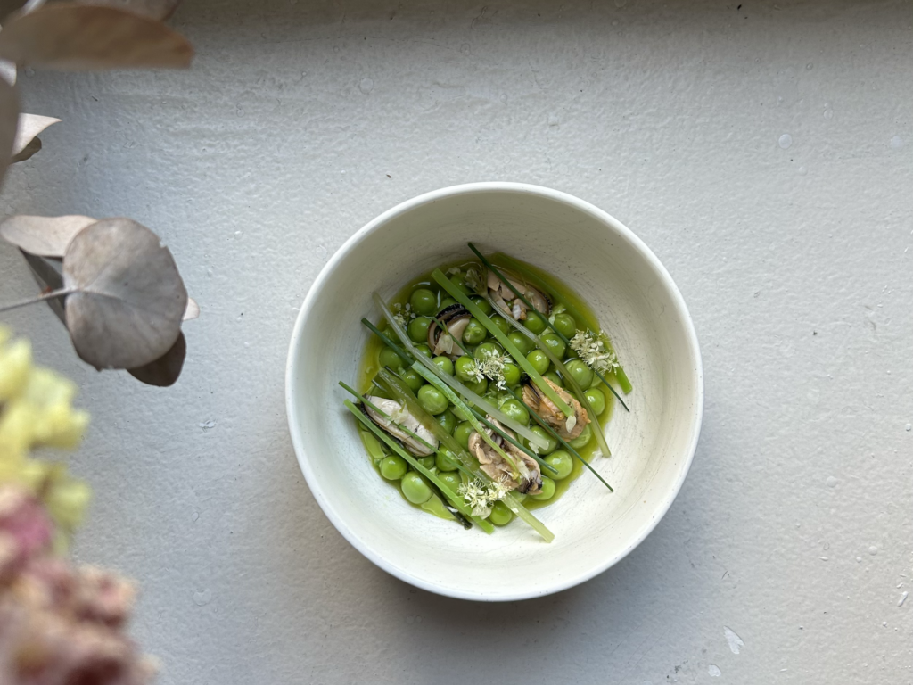 Ravintola Wellamon herneistä ja simpukoista koostuva annos valkoisessa kulhossa.