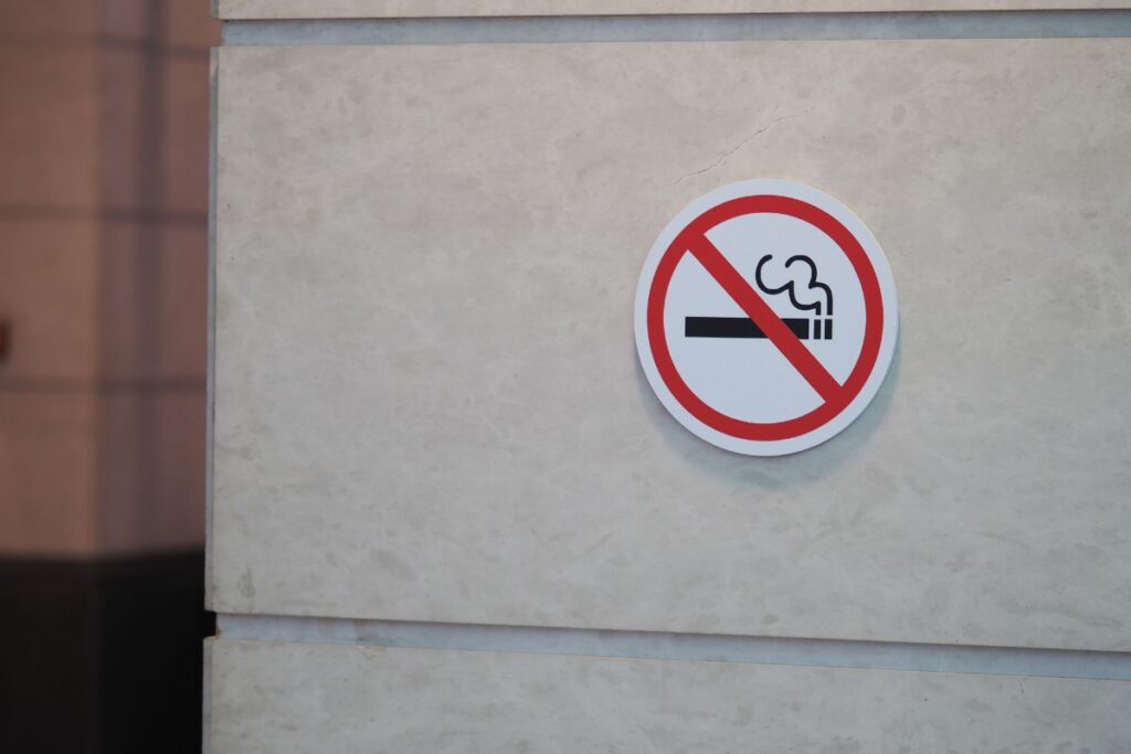 Tupakointi kielletty kyltti harmaalla talon betoniseinällä. 
