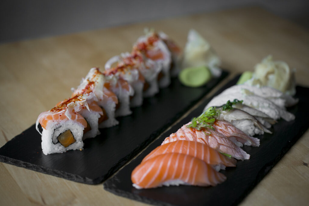 Sushiannoksia mustilla tarjoilualustoilla, nigiriä ja lohirullia.
