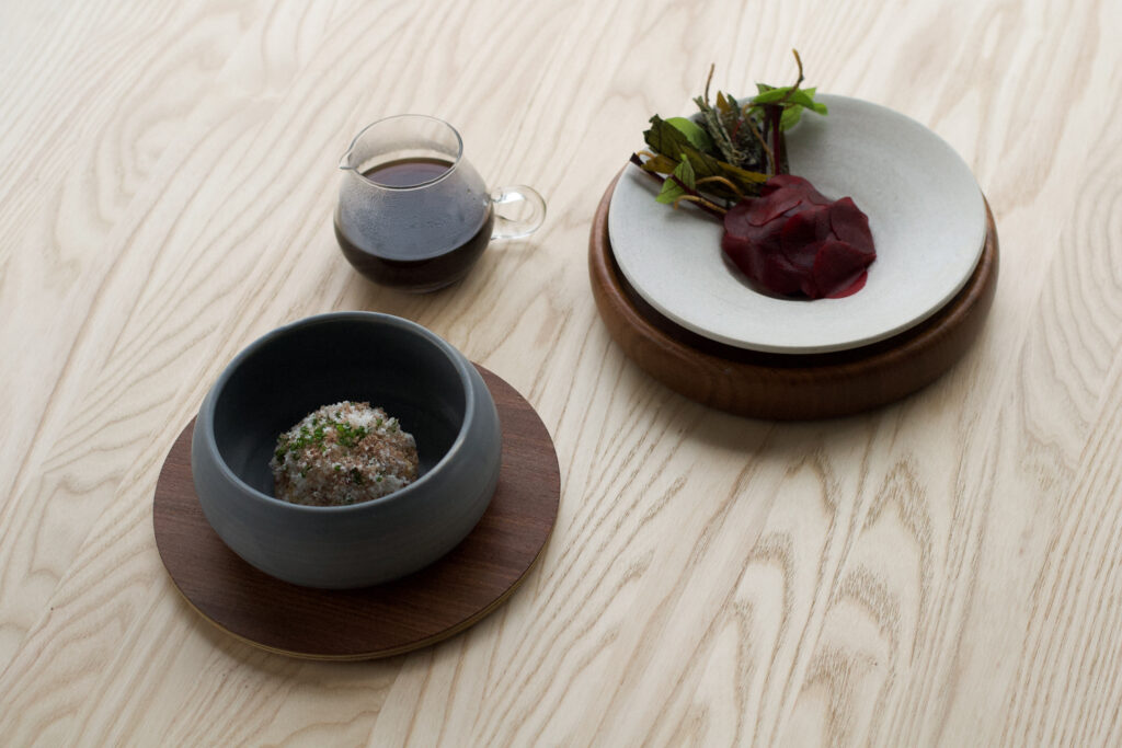 Ravintola Kaskiksen minimalistisesti aseteltuja gourmet-annoksia keraamisissa astioissa puupöydällä.