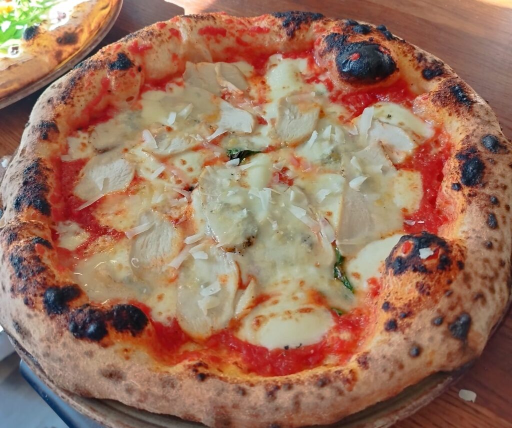 Uunissa paistettu pizza, jossa on tomaattikastiketta, sulatettua juustoa ja rapea reunus.