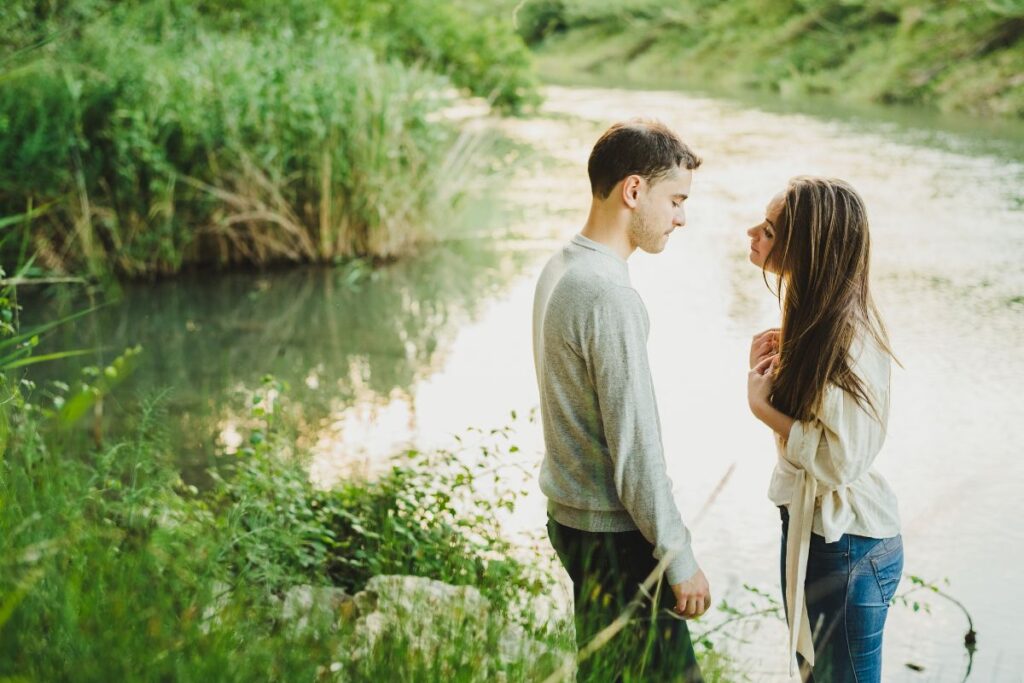 Nainen ja mies seisovat joella ja katsovat toisiaan hiljaisuuden vallitessa.