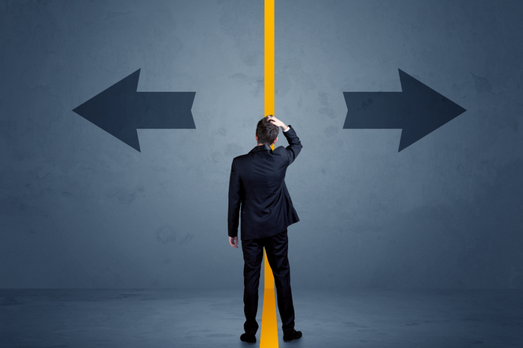 Mies seisoo tienjakajalla ja raapii päätään kahden vastakkaisen nuolen välissä, symboloiden vaikeaa päätöksentekoa.