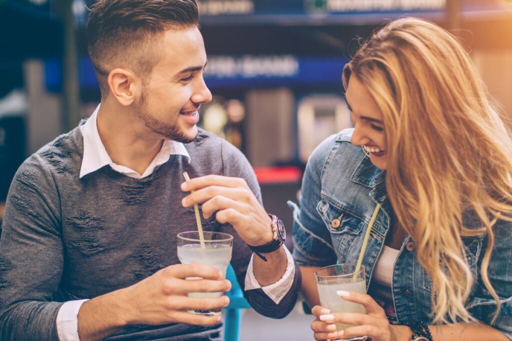 Pariskunta nauraa ja juttelee juomien äärellä kaupungilla.