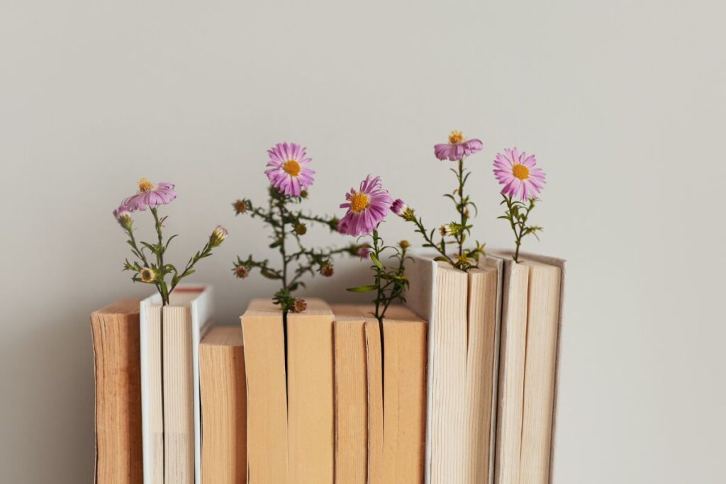 Kirjapino, jonka väliin on asetettu vaaleanpunaisia kukkia vaaleaa taustaa vasten.