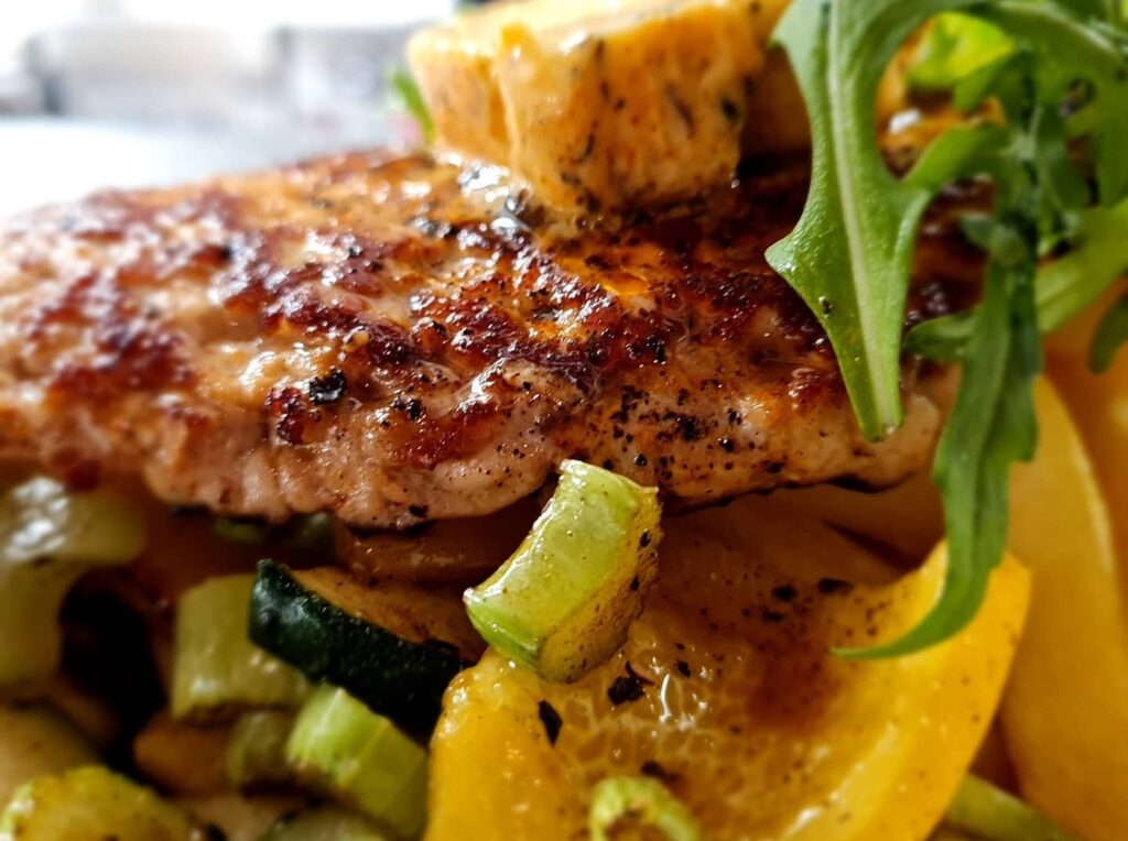 Lähikuva ruoka-annoksesta, jossa lehtipihvin kanssa lämpimiä kasviksia ja rucolaa.