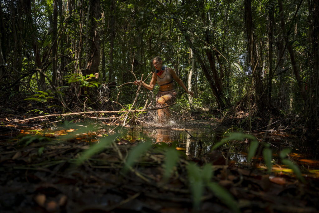 Kilpailija kahlaa viidakkopuroa pitkin tiheässä sademetsässä Selviytyjät-ohjelmassa.