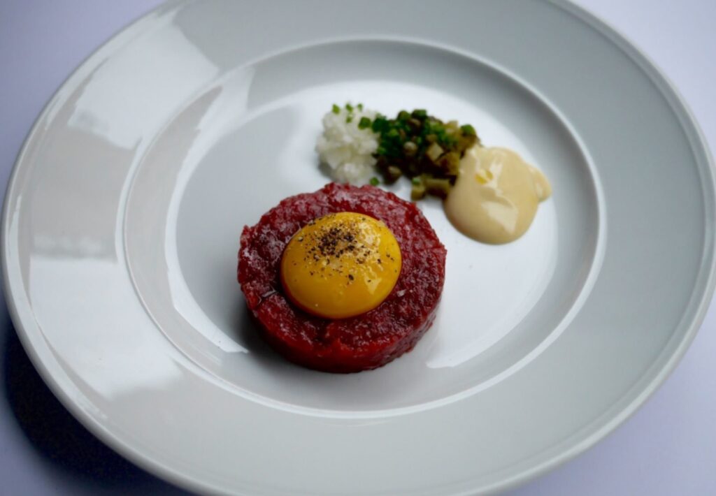 Ravintola-annos tartaria, jonka päällä raaka kananmunan keltuainen.